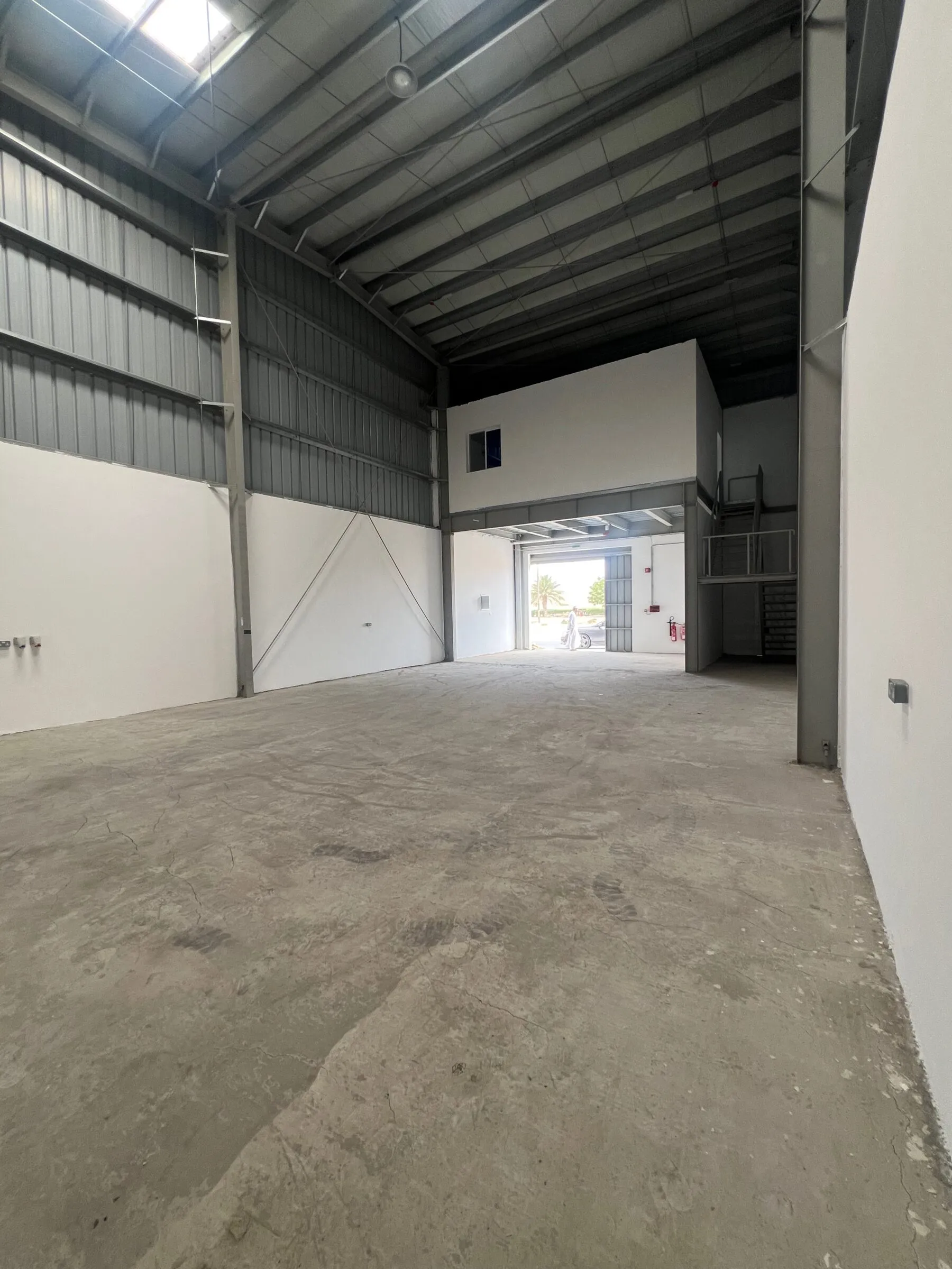 The empty warehouse before work began — bare concrete slab, metal cladding and a single roller door.